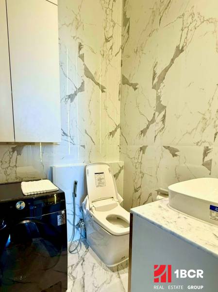 Fürdőszoba egy 4 szobás lakásban WC-vel, mosógéppel és márványfalakkal.