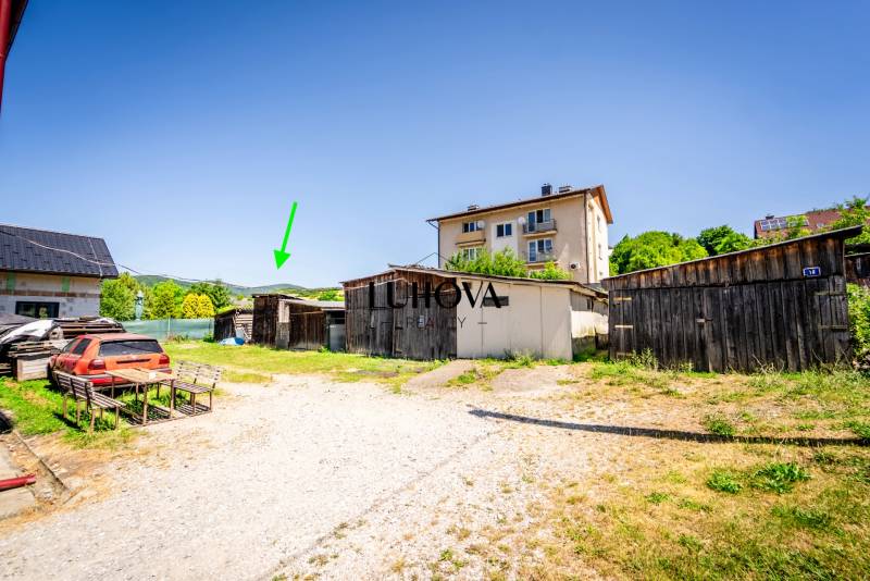 Udvar néhány faépülettel és parkoló autóval Púchovban, egy 2 szobás lakásnál.