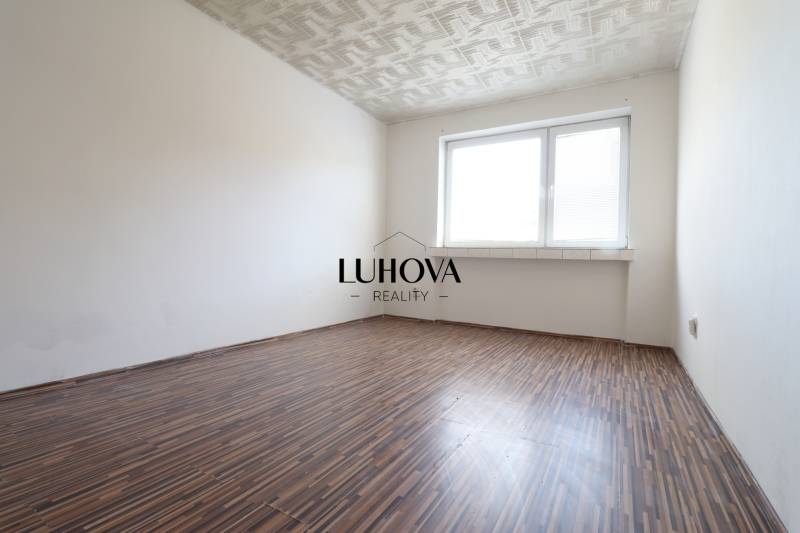 Egy üres szoba mintás padlóval és nagy ablakkal egy kétszobás lakásban.