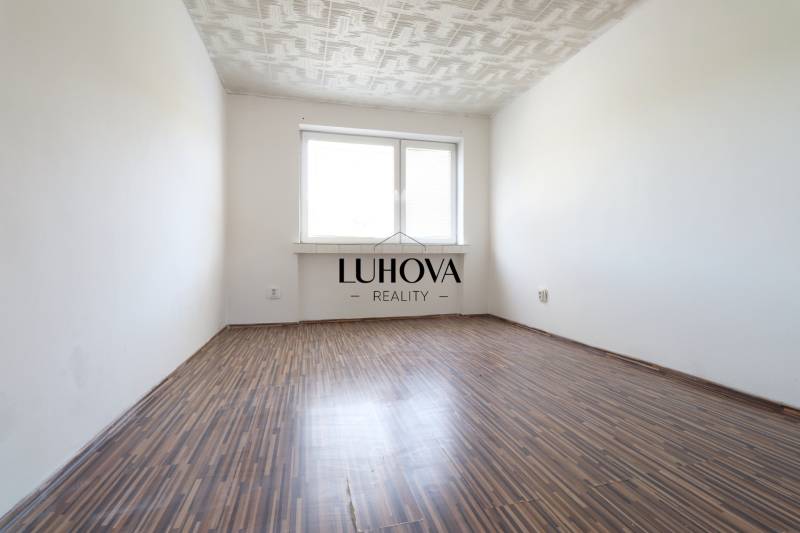 Üres szoba fa padlóval és fehér mennyezettel egy kétszobás lakásban.