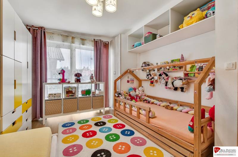 Gyerekszoba családi házban játékokkal és színes szőnyeggel.