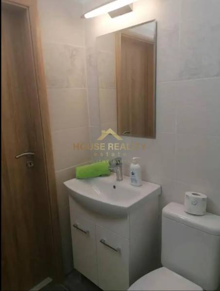 Fürdőszoba mosdóval, tükörrel és WC-vel egy egyszobás lakásban.
