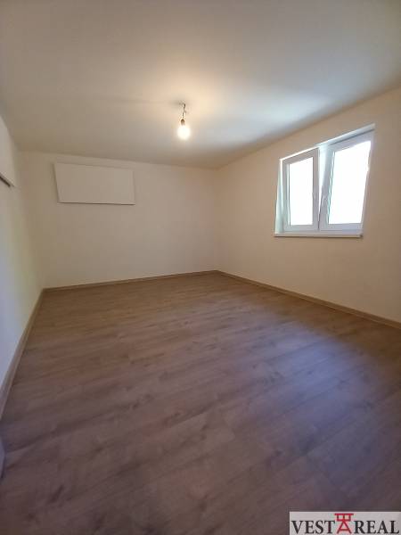 Üres szoba laminált padlóval és fehér falakkal egy családi házban.