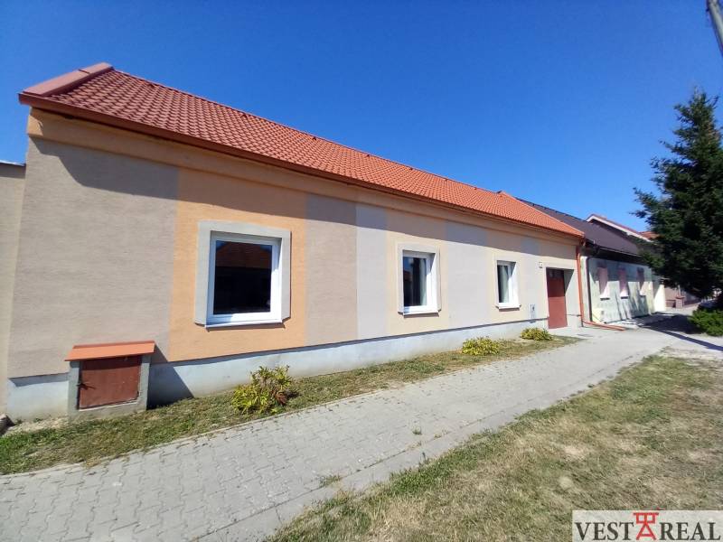 Családi ház Trakoviceben narancssárga homlokzattal és piros tetővel.