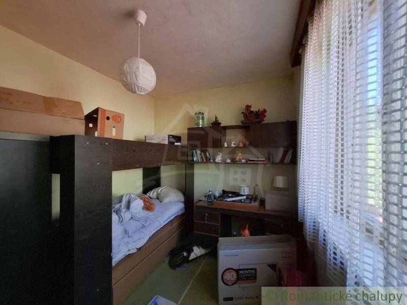 Szoba családi házban ággyal, asztallal és polccal.