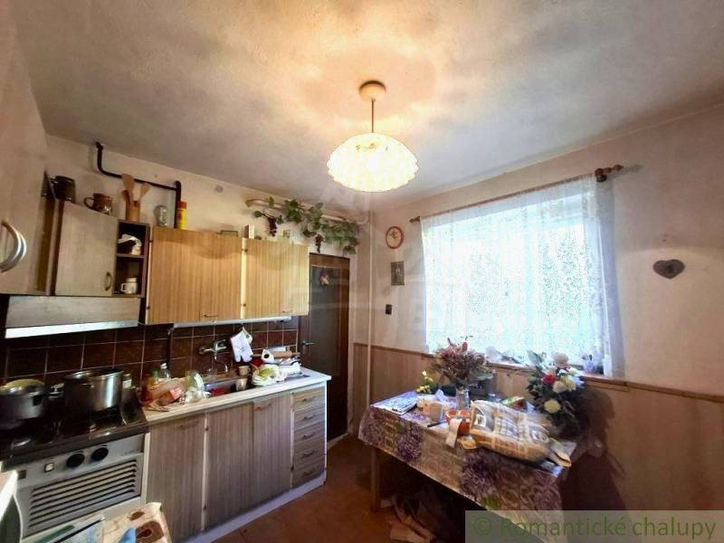 Konyha egy családi házban konyhapulttal, asztallal és virágokkal az ablakban.