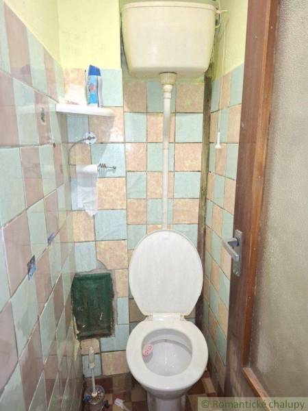 Egyszerű fürdőszoba egy családi házban régebbi WC-vel és csempékkel.