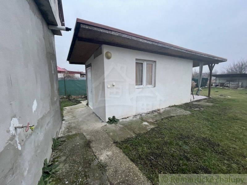 Kerti pavilon családi ház mellett, szilárd burkolatú területen, gyepesítéssel és kerítéssel.