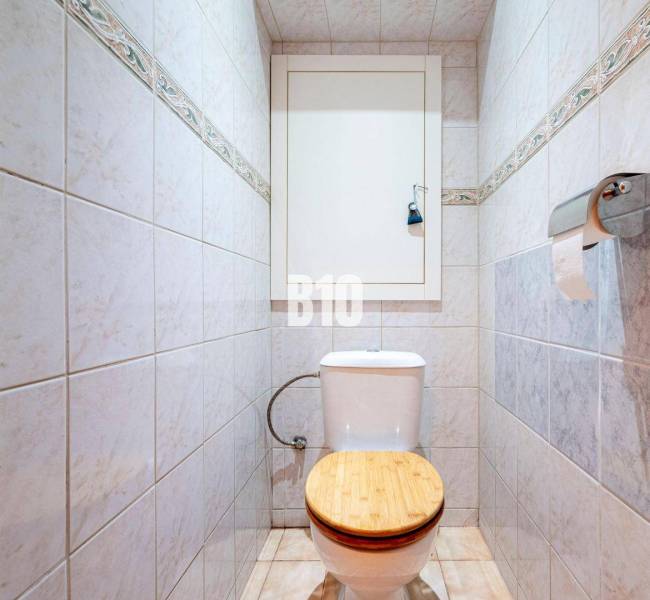 WC csempékkel a háromszobás lakásban, fa ülőke, papírtartó.