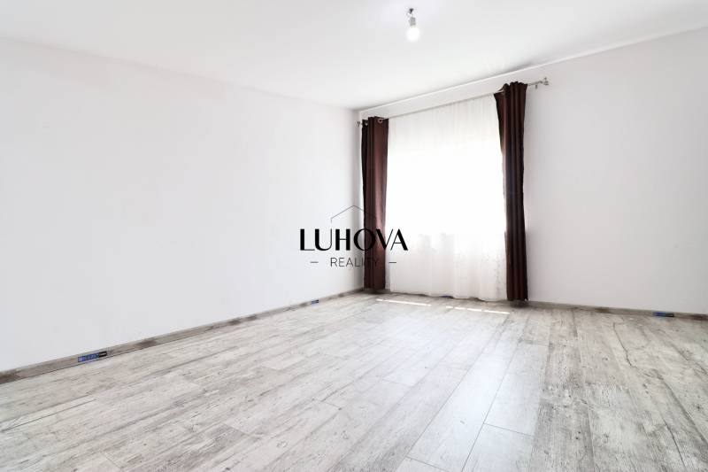 Egy üres szoba fehér falakkal, barna függönyökkel és fa padlóval egy családi házban.