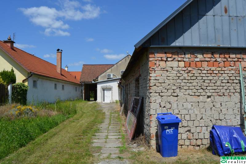 Kereskedelmi helyiségek Borsky Svätý Jurban, piros tetős épületek, gyep és kék konténer.