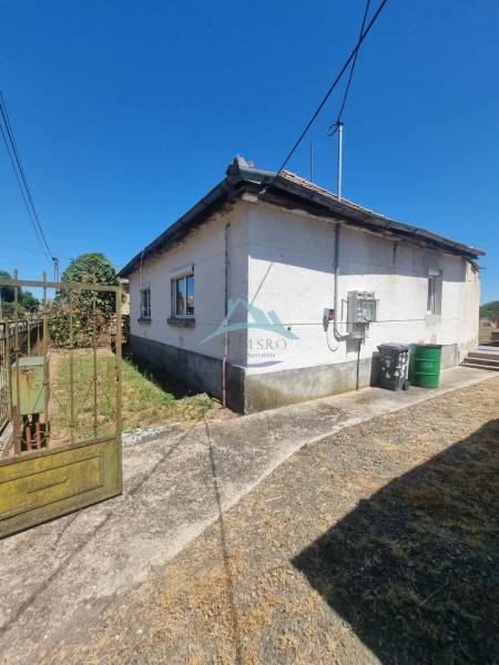 Családi ház Ipolyvecen régi tetővel, borús járda és elektromos vezeték.