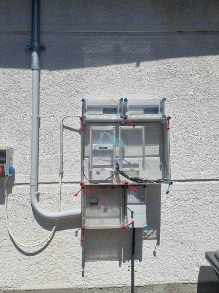 Elektromos vezetékek elosztása a családi ház homlokzatán Ipolyvecén.