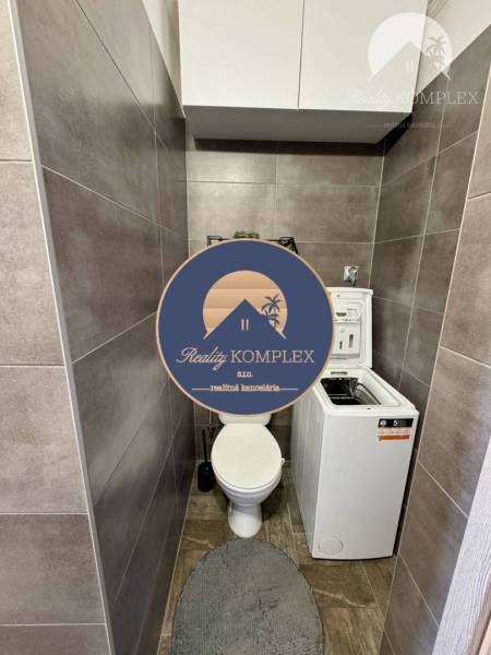 WC mosógéppel egy 4 szobás lakásban, szürke csempével burkolva és tárolószekrényekkel.