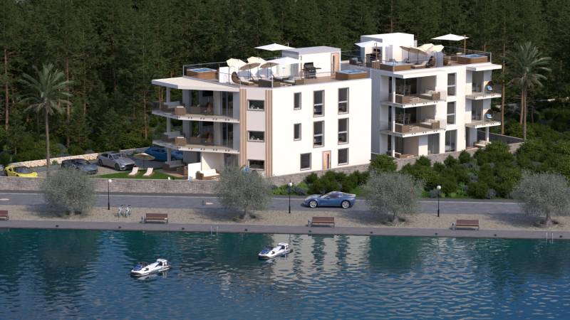 Modern épület a vízfelület mellett, zölddel és pálmafákkal körülvéve, parkolóval.