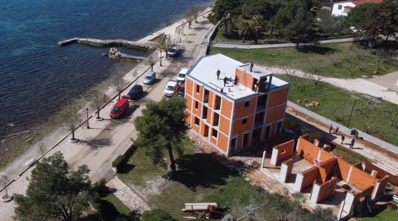 Épület a tenger mellett Vir városában, megközelítési úttal és zöldterülettel.