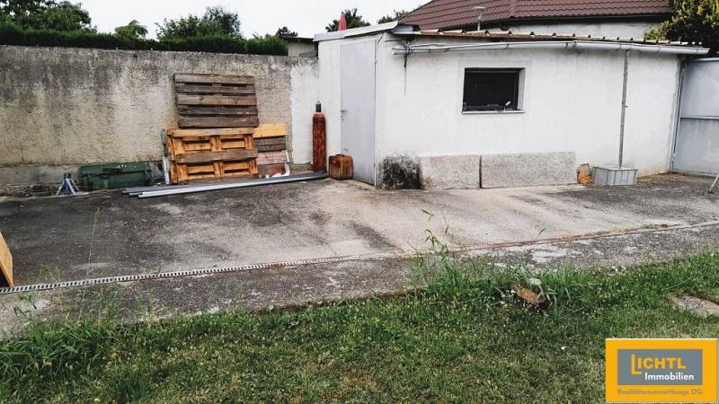Udvar egy családi ház mellett a 2473 Potzneusiedl-ben betonfelülettel és fa raklapokkal.