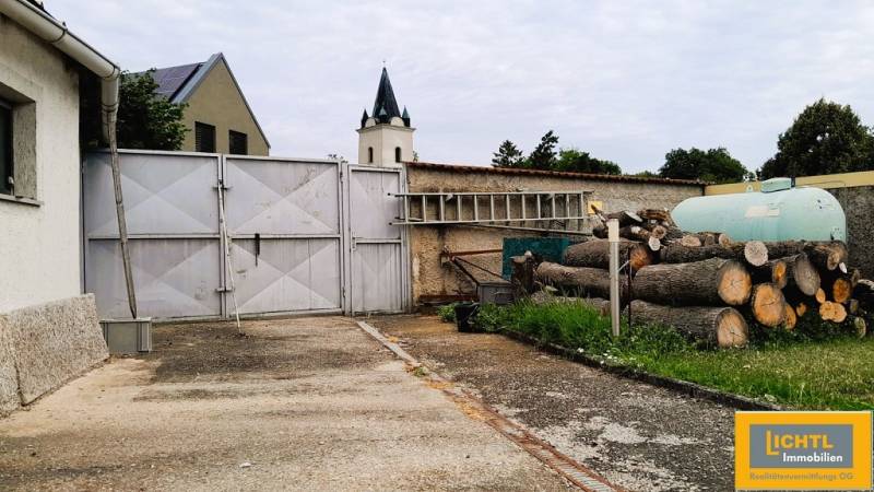 A családi ház bejárati udvara Potzneusiedl 2473-ban, kapuval és felhalmozott fával.