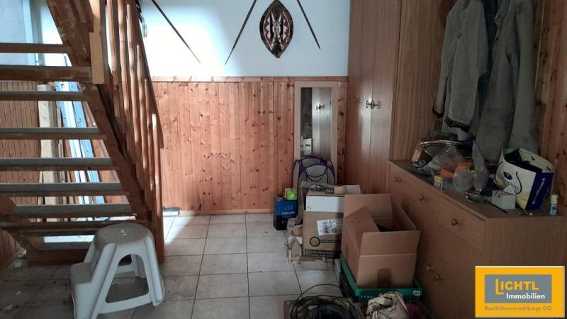 Fa lépcső és tárolóhely egy családi házban dobozokkal és kabátokkal.