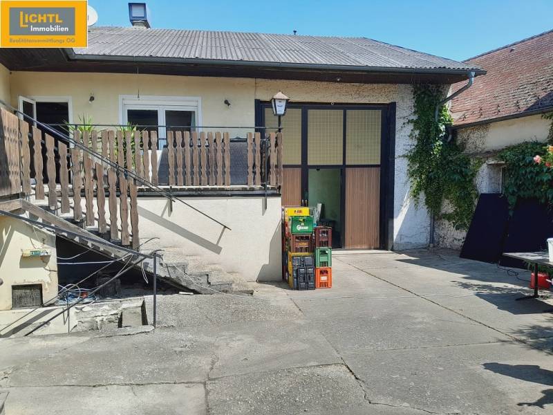 Udvar lépcsőházzal a Grossinzersdorf-i Gasztro térben, zölddel és sörrekeszekkel körülvéve.
