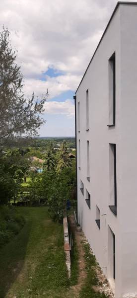 Fehér homlokzatú villa Hainburg an der Donau városában, kilátással a kertre és a fákra.