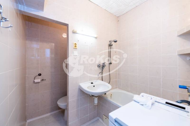 Fürdőszoba egy kétszobás lakásban zuhanyzóval, mosdóval és WC-vel.