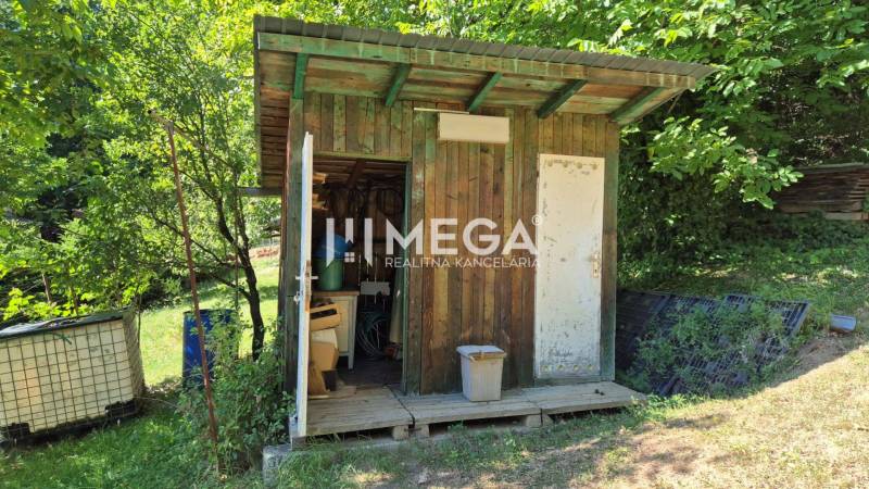 Egy fa pavilon a homonnai kertekben, zölddel és vízhordó hordókkal körülvéve.