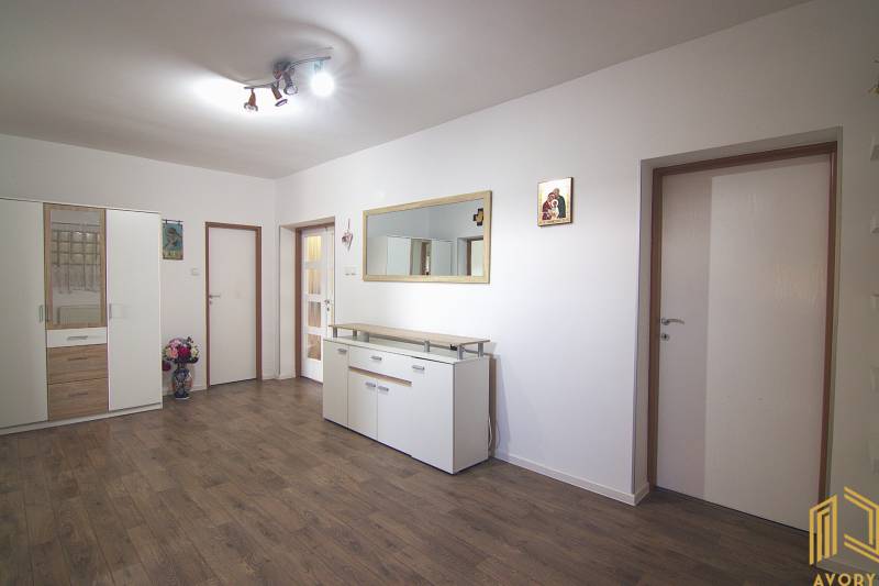 Családi ház belső tere fehér bútorokkal, fa dekoros padlóval és nagy tükörrel.