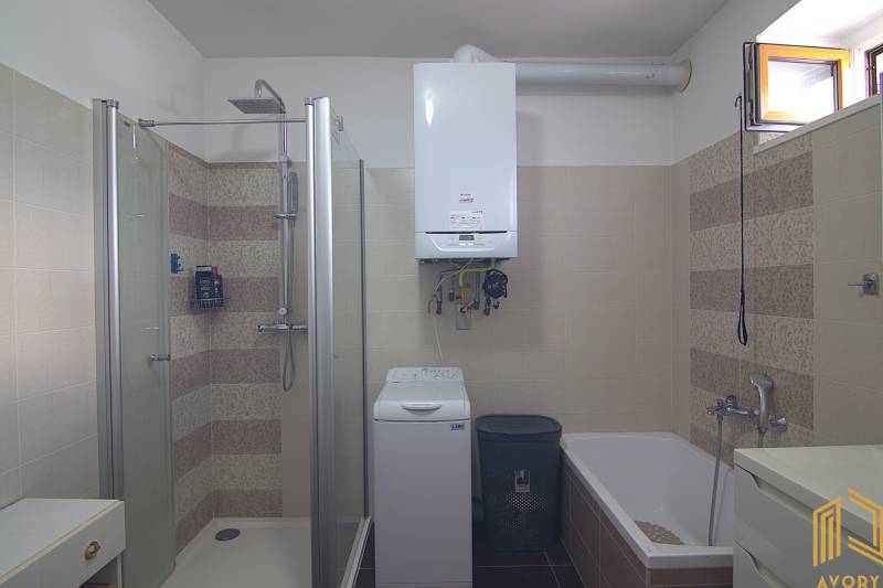 Fürdőszoba káddal, zuhanyzóval, mosógéppel és gázkazánnal a családi házban.