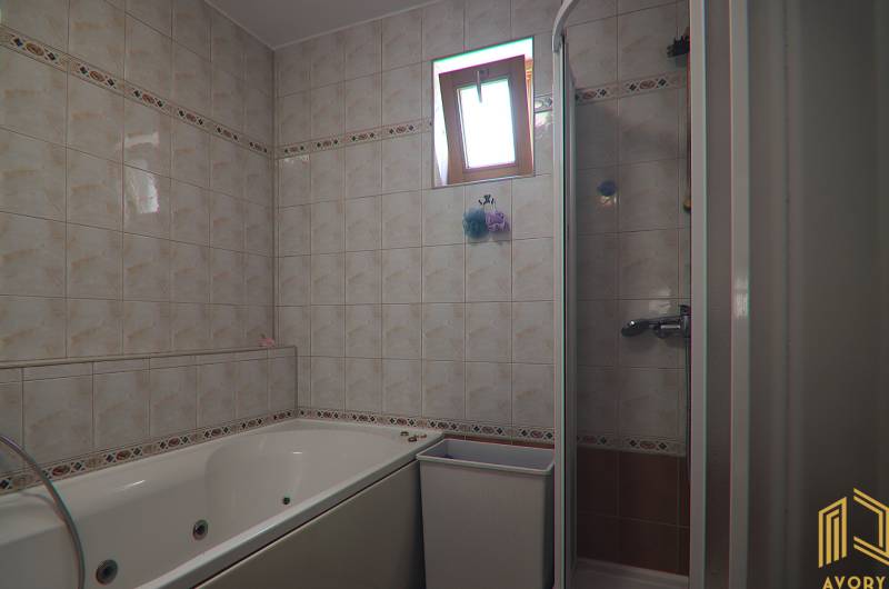 Fürdőszoba családi házban csempével, káddal és zuhanyzóval.