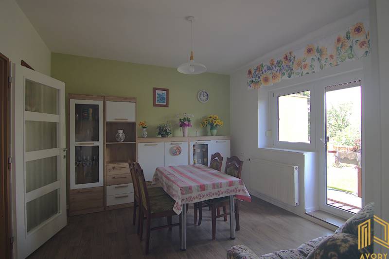 Családi ház ebédlője asztallal, székekkel és díszekkel ellátott szekrénnyel.