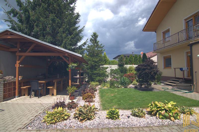 A Sport utcai családi ház kertje Brodskóban, pavilonnal és virágágyásokkal.