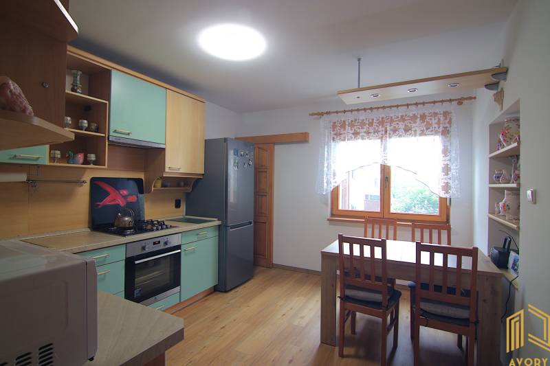 Családi ház konyhája konyhabútorral, asztallal és székekkel.