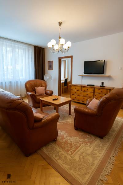 Nappali egy kétszobás lakásban bőr ülőgarnitúrával és fa bútorokkal.