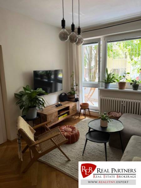 Nappali kanapéval, TV-vel és szobanövényekkel egy 4 szobás lakásban.
