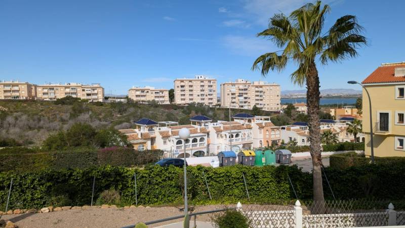 Kilátás lakóházakra, fákra és konténerekre a cl. Aquiles utcában, Torreviejában.