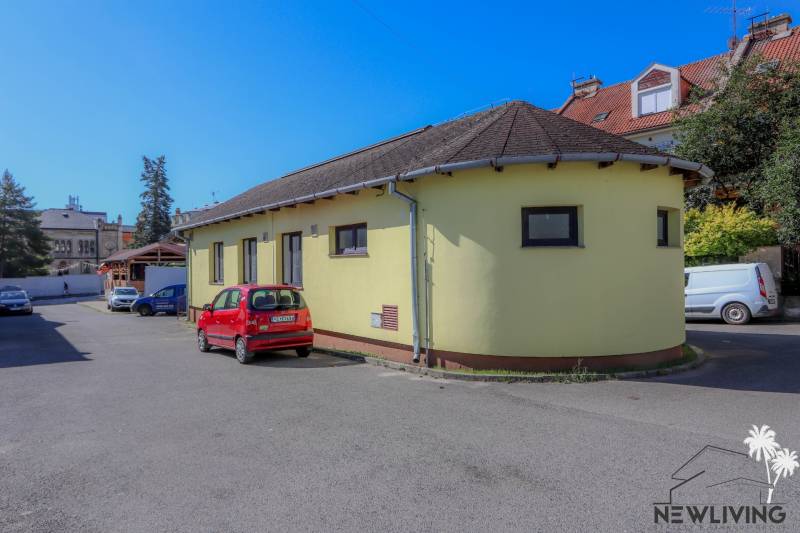 Sárga épület a Szlovák Nemzeti Felkelés utcában, Vrbové városában, parkoló piros autóval.