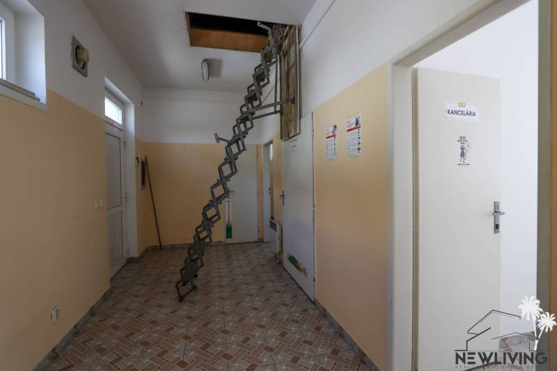 Kereskedelmi helyiségek belső tere létrával, amely a padlásra vezet, és jobbra egy irodával.
