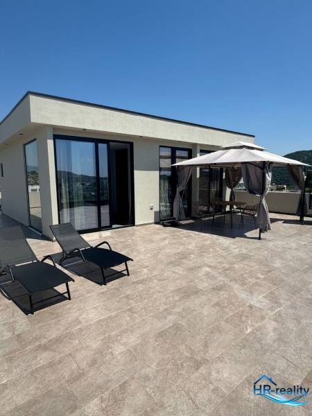 Nyaraló apartman Ksamilban terasszal, napozóágyakkal és kerti pavilonnal a pihenéshez.