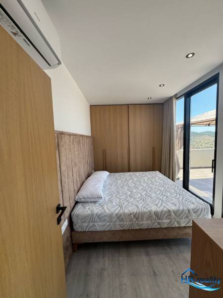 Hálószoba a nyaraló apartmanban kényelmes ággyal, ízléses berendezéssel és erkéllyel.
