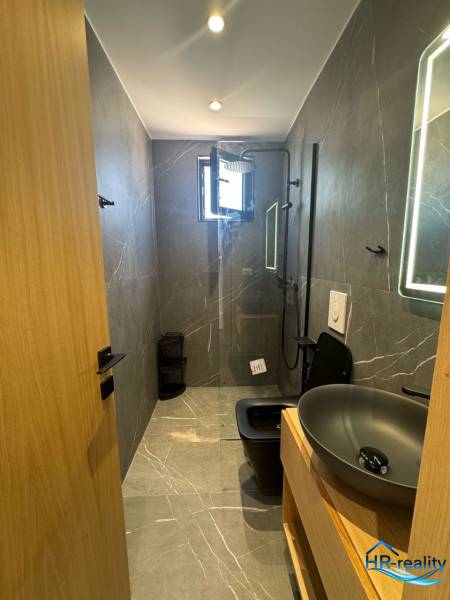 Fürdőszoba a nyaraló apartmanban zuhanyzóval, modern mosdóval és sötét WC-vel a kényelem érdekében.