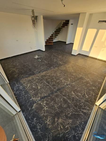 Nyaraló apartman sötét padlóval, fehér falakkal és lépcsővel.