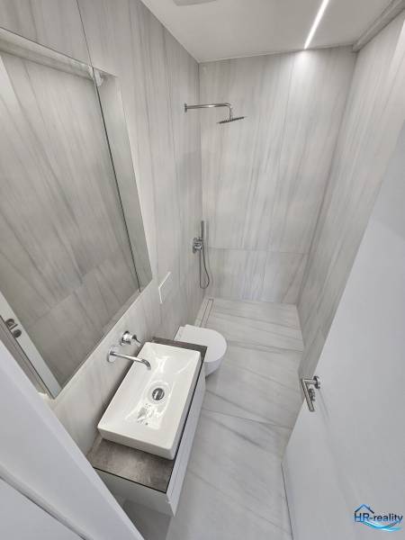 Fürdőszoba a nyaraló apartmanban zuhanyzóval, mosdóval és WC-vel.