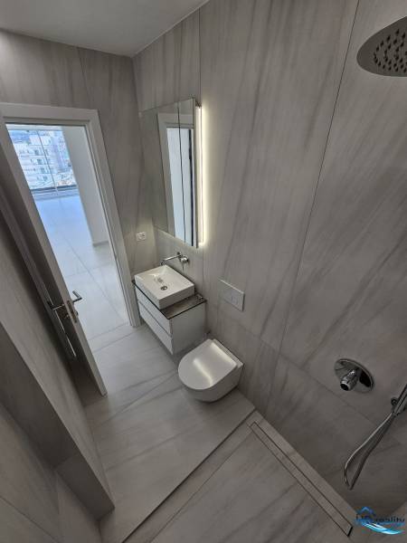 A nyaraló apartman fürdőszobája mosdóval, zuhanyzóval és ízléses világítással.