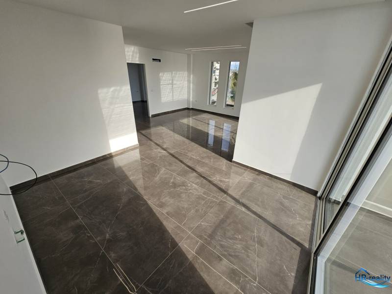 Nyaraló apartman belső tere nagy ablakokkal és fényes csempével.
