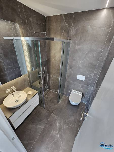 A nyaraló apartman fürdőszobája tágas zuhanyzóval és modern felszereléssel.
