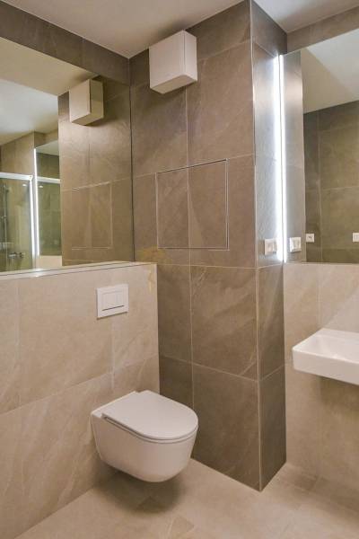 Fürdőszoba függesztett WC-vel és zuhanyzóval egy háromszobás lakásban.