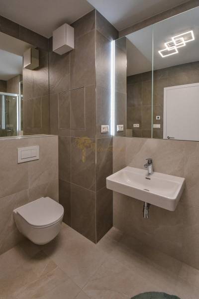 Fürdőszoba függesztett WC-vel, mosdóval és zuhannyal egy háromszobás lakásban.