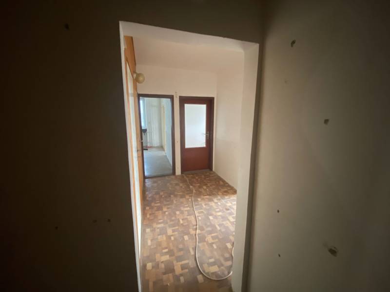 Egy 3 szobás lakás folyosója fa padlóval és két szobával.