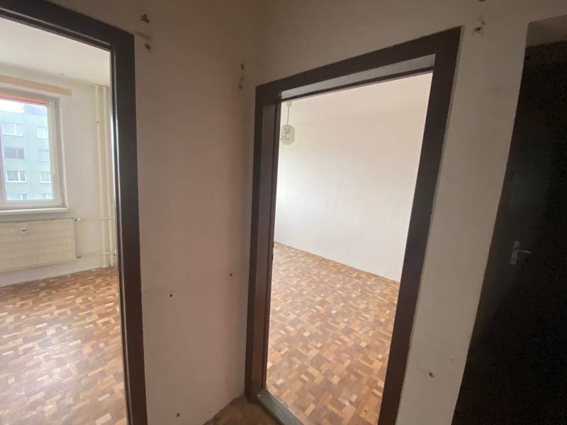 Előszoba egy 3 szobás lakásban, parketta, két szobába nyíló bejárat, ablak kilátással.